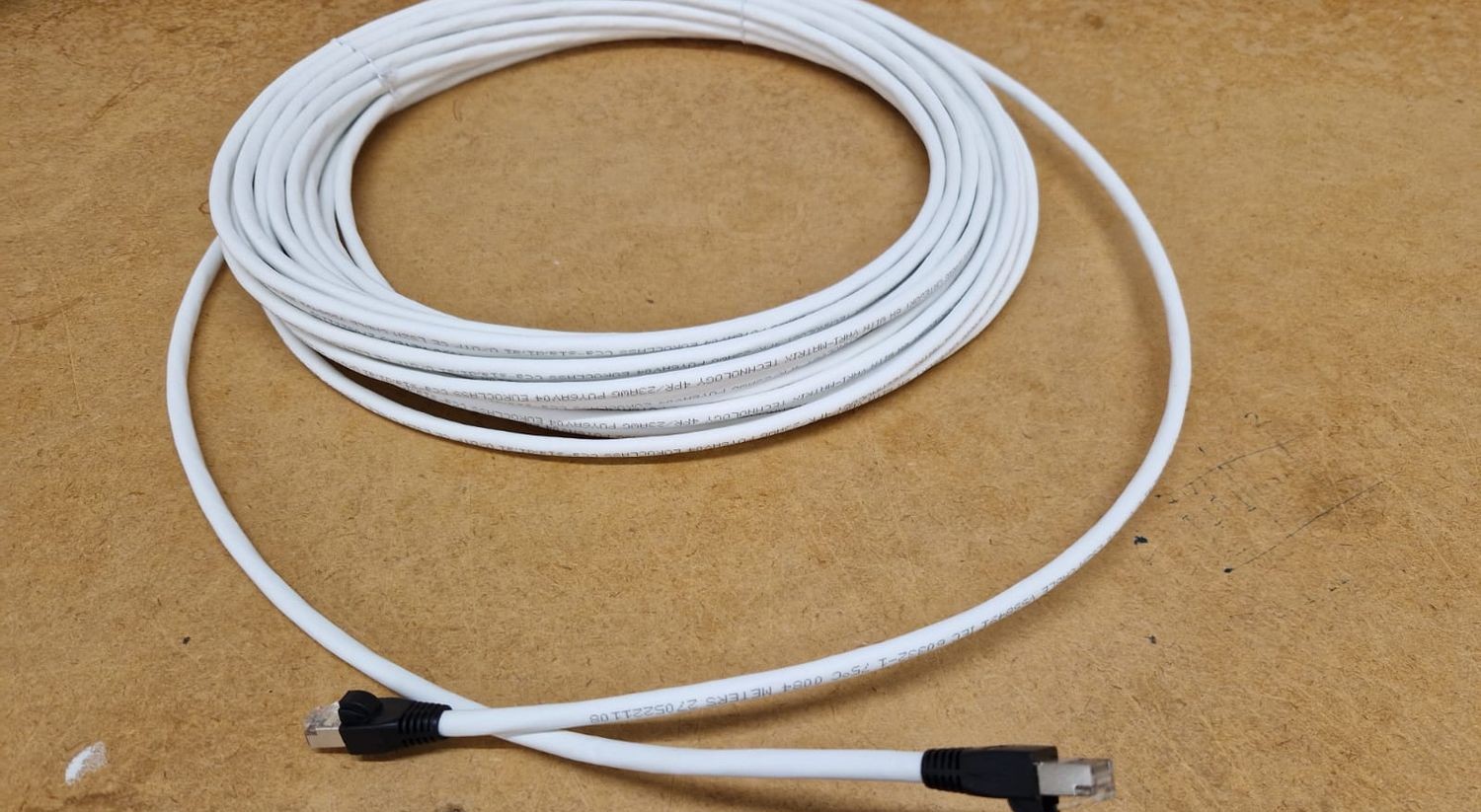 Coiled white copper patch cable with an RJ45 plug at each end