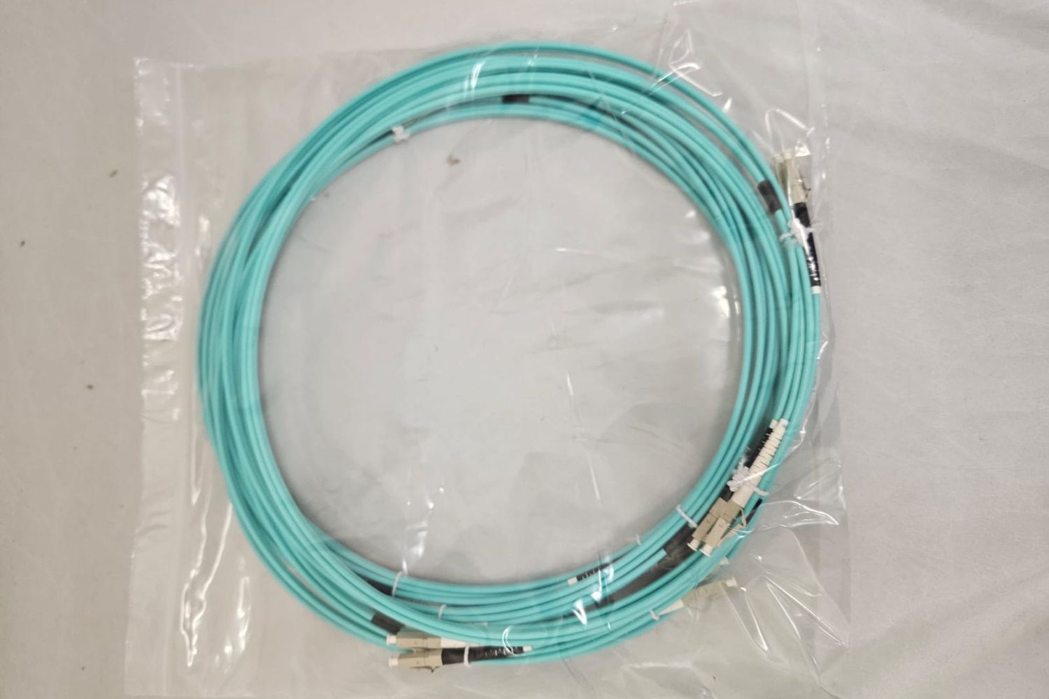 Aqua multimode fibre patch cable, coiled in its bag with duplex connectors