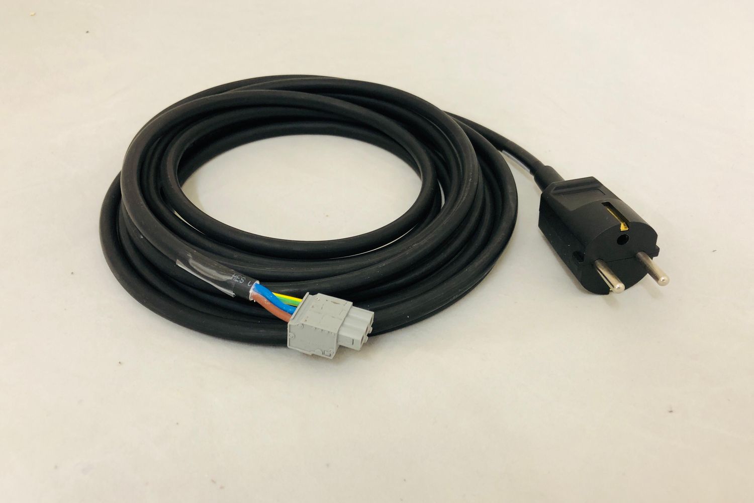Coiled black power cable assembly with a moulded mains plug and a grey multi-pin connector