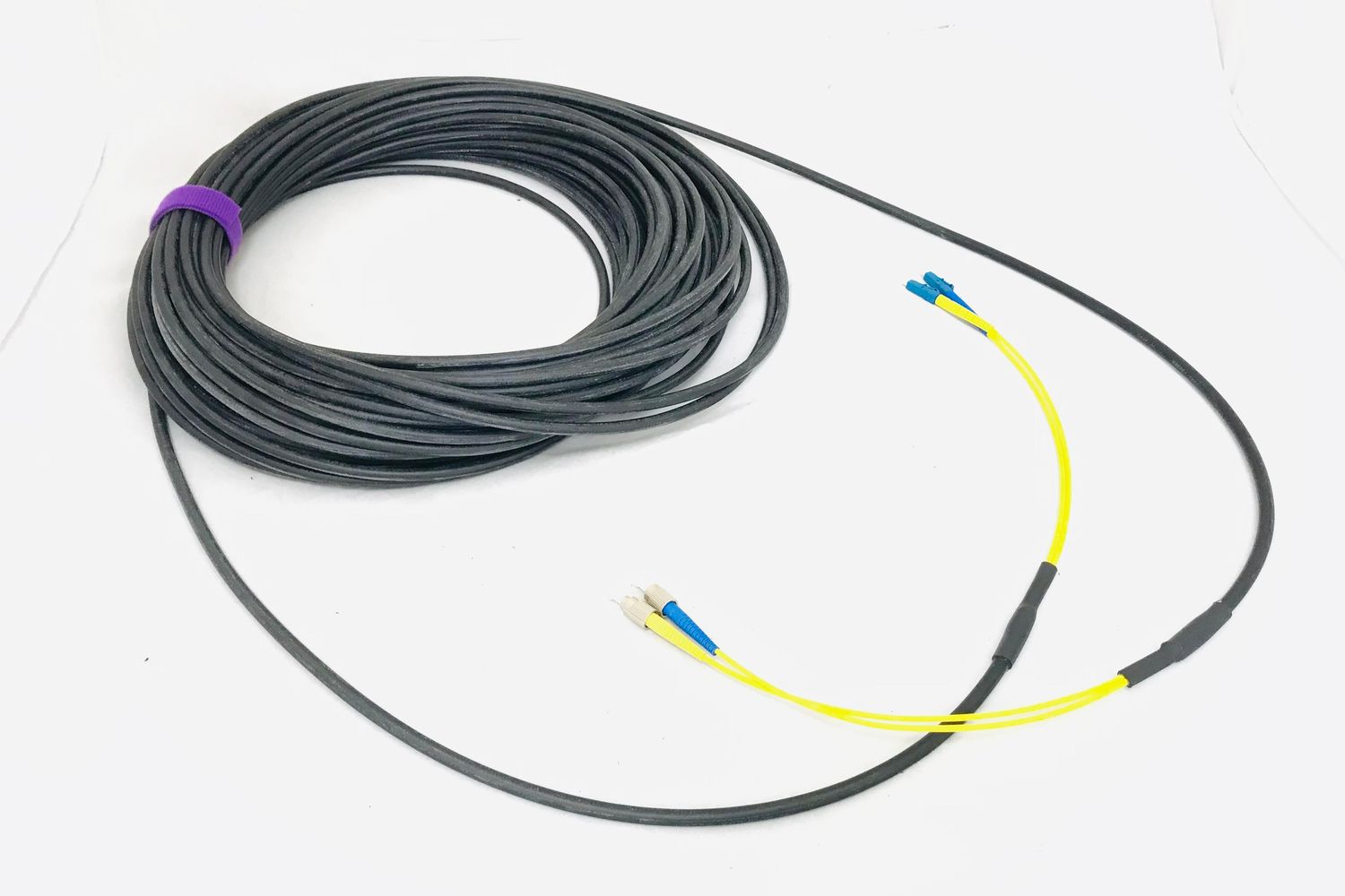Coiled black micro armoured fibre cable breaking out into yellow legs with blue connectors